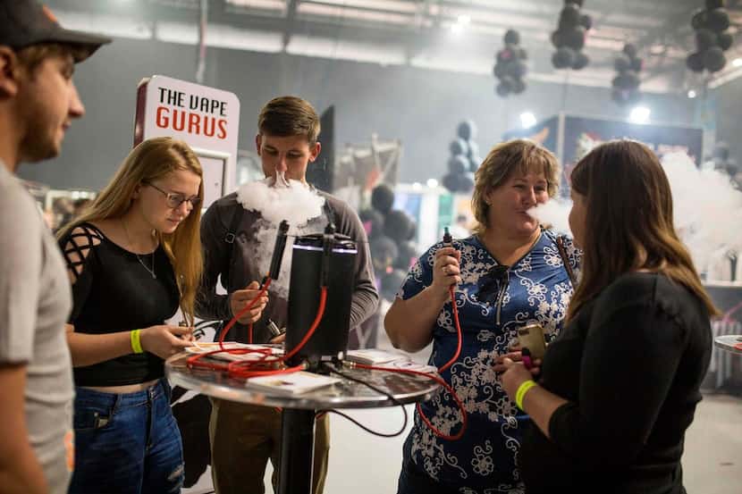 People try different electronic cigarettes on stands during VapeCon in Pretoria, South...