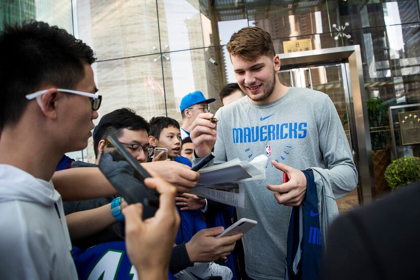 Dallas Mavericks guard Luka Doncic signs autographs for fans as the team departs their hotel...