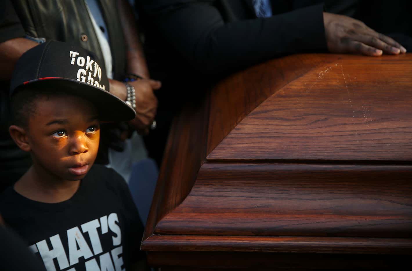 King Solomon Grayson, 6, of Duncanville, Texas, stands near two empty coffins symbolizing...