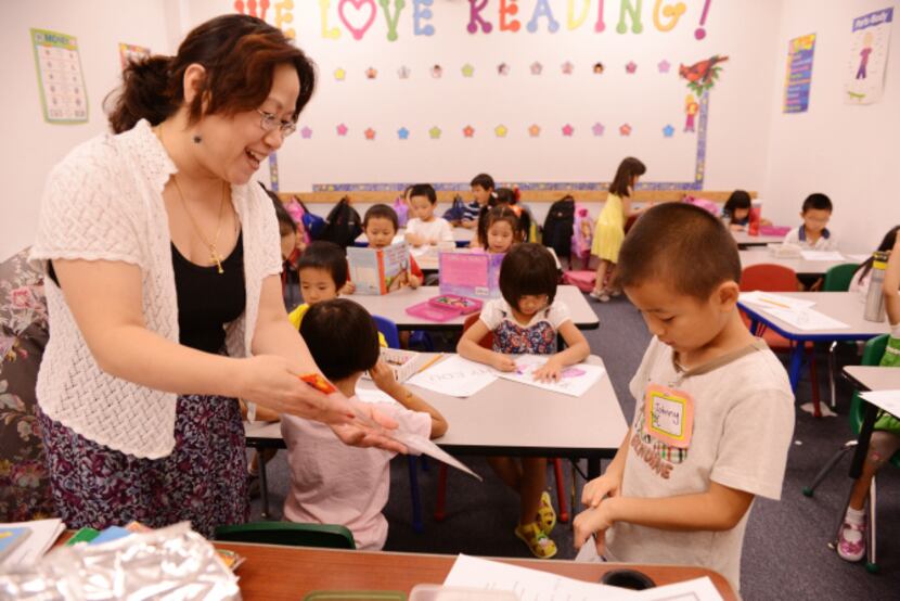 Teacher Ellen Pang gives a sticker to Johnny Yu after completing his school work at Hua Yi...