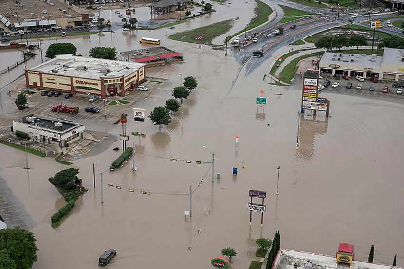 Floodwaters from the Blanco River cover a shopping center parking lot Sunday on State...