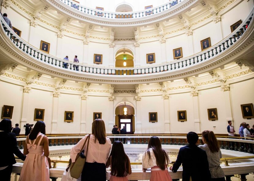 People look down from the balcony in the rotunda of the Texas State Capitol during the first...