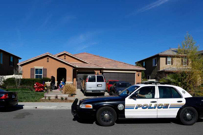 A Perris police car drives past the home of David and Louise Turpin where police arrested...