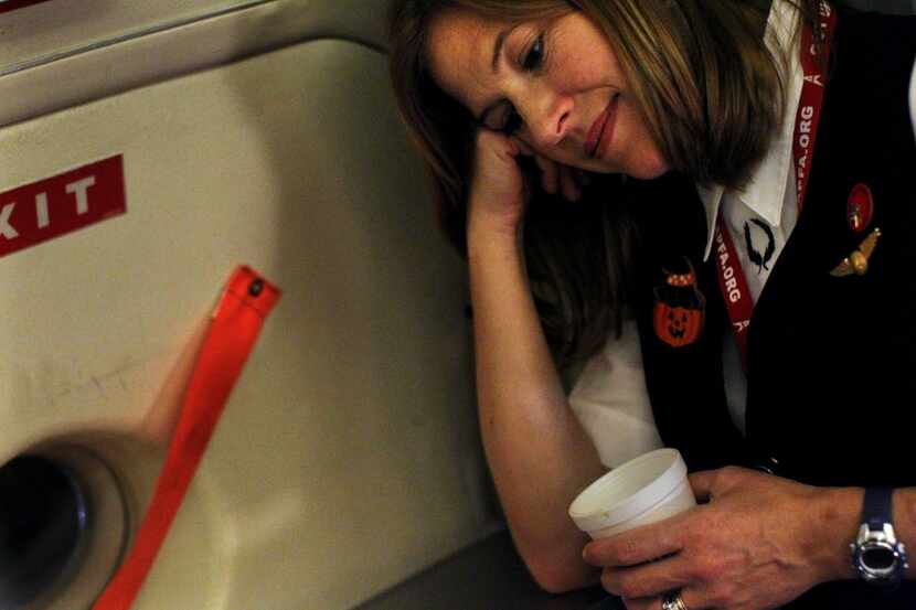 American Airlines flight attendant Kristen Heller rested for a moment as she waited for...