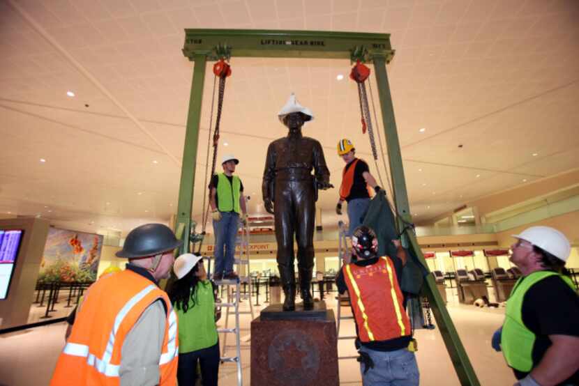Workers remove protective material from the One Riot, One Ranger statue at Love Field after...