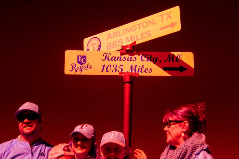 Fans pose for photos near a sign showing the distances to the homes of the Texas Rangers and...