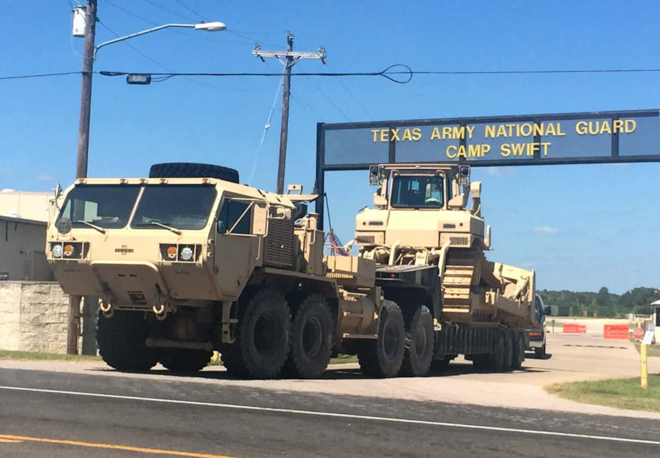 Heavy equipment rolls out of one of the gates to Texas Army Nation Guard Camp Swift outside...
