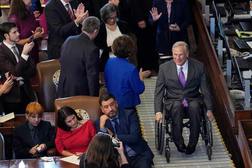 Texas Gov. Greg Abbott, right, arrives in the House Chamber at the Texas Capitol during the...