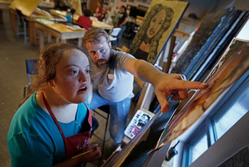 Art teacher Casey Parrott (right) helps his student Rosie Alvarado paint a portrait of...
