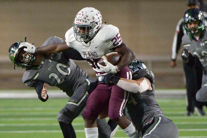 Plano's Tylan Hines tries to run through the tackle attempts by Prosper's Will Schreve (20)...
