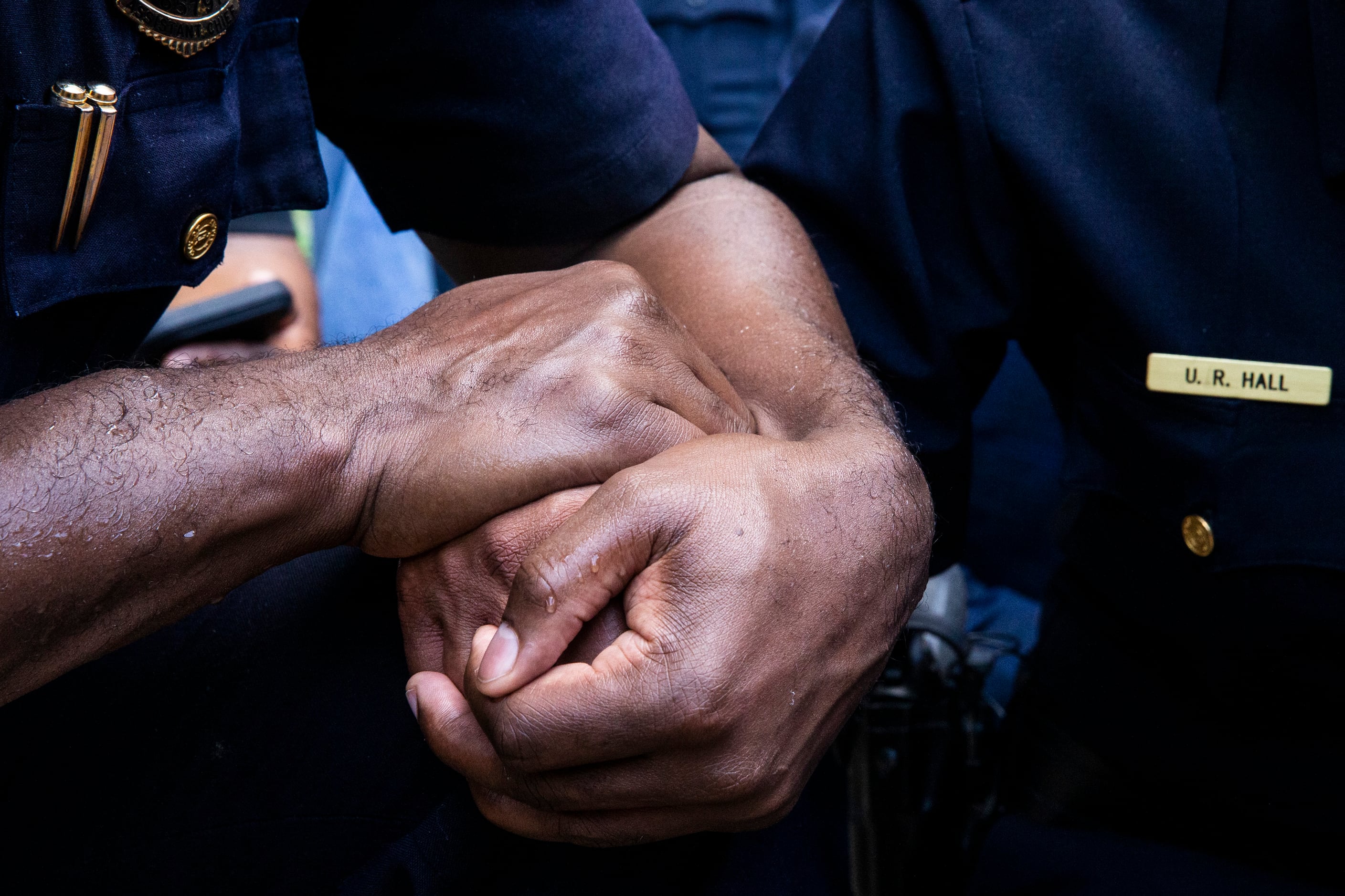 An officer holds the hand of Chief U. Renee Hall (center) as she weeps while kneeling with...