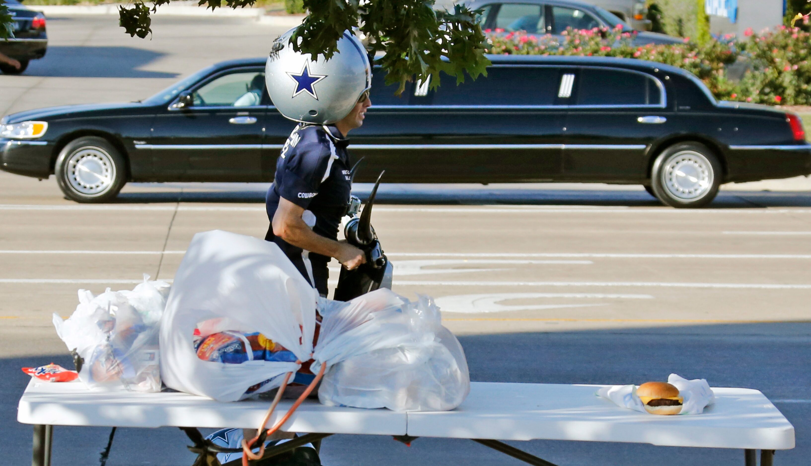 A Cowboys fans motors by on a segue, as a limousine passes in the background along Randol...