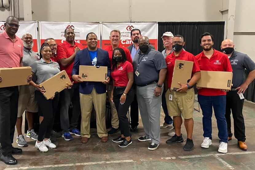 A group of Coca-Cola Southwest Beverages volunteers in polo shirts hold boxes.