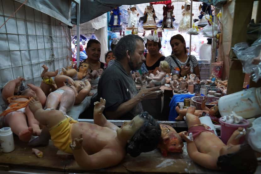 Maximino Vértiz Quintanilla repara la estatua del niño Dios de un cliente dentro de su...