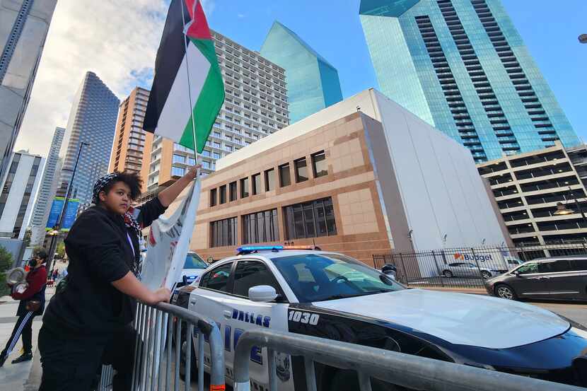 Lee Mulupi, 19, a member of the DFW Anti War Committee, waves a Palestinian flag at a rally...