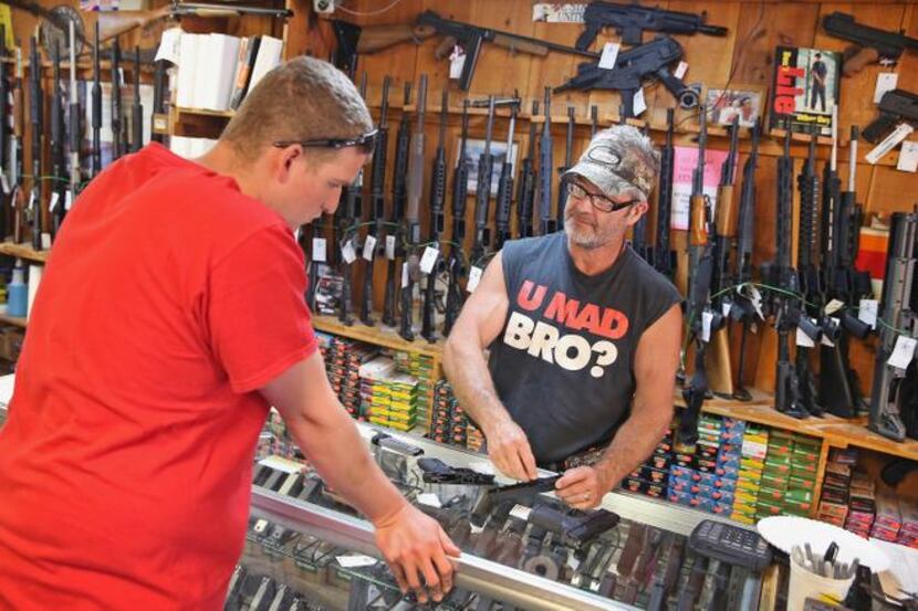 
Danny Egan (right) helps a customer shop for handguns at Freddie Bear Sports in Tinley...