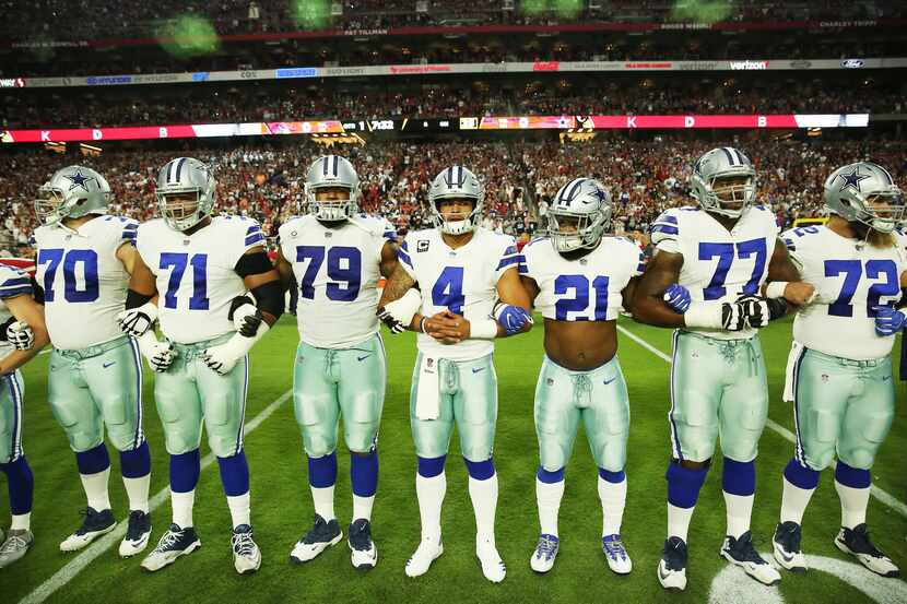 Dallas Cowboys teammates lock arms before the playing of the national anthem before their...
