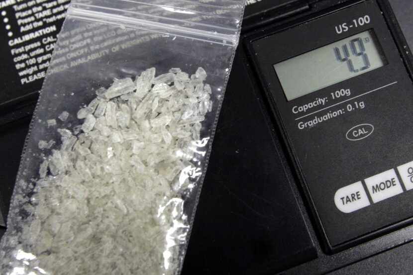 An official weighs some "Ice," a clear crystal-type methamphetamine. Seven people, including...