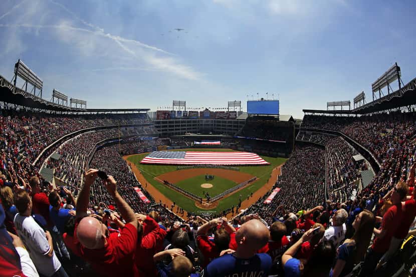 Fans watch as vintage planes fly overhead during the National Anthem before the Texas...