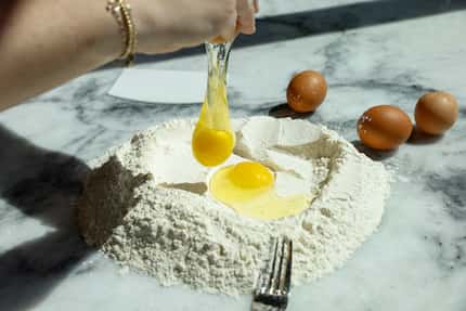 Owner Leigh Hutchinson cracks an egg over flour as she makes pasta at Via Triozzi, Thursday,...