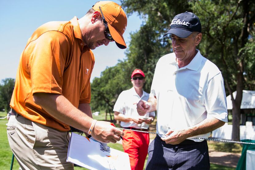 University of Texas football coach Tom Herman, left, signs an autograph for Greg Bazard of...