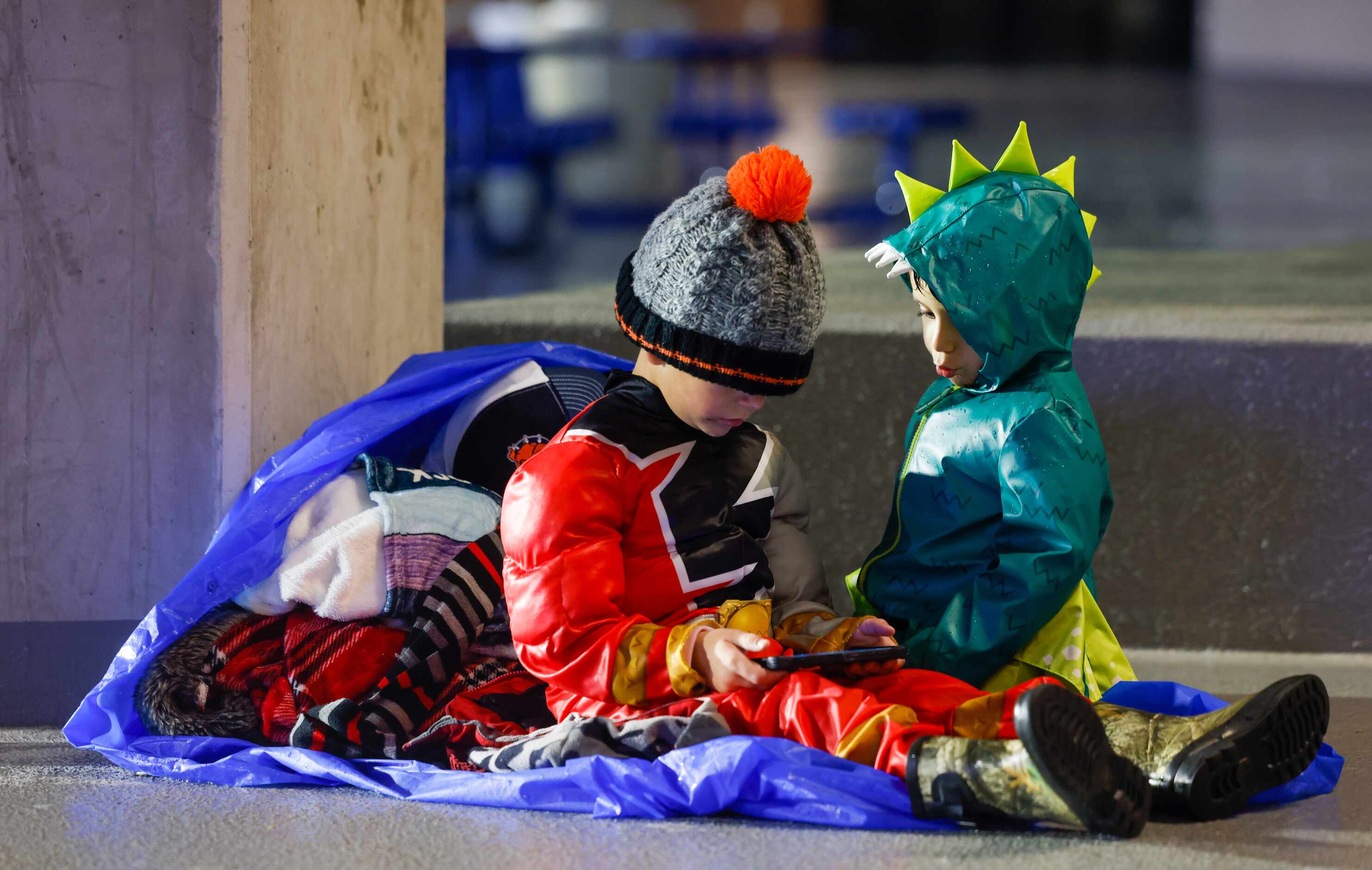 Wyatt Kubie (left), 4, plays a game to wait out weather delays while Benjamin Garcia, 3,...