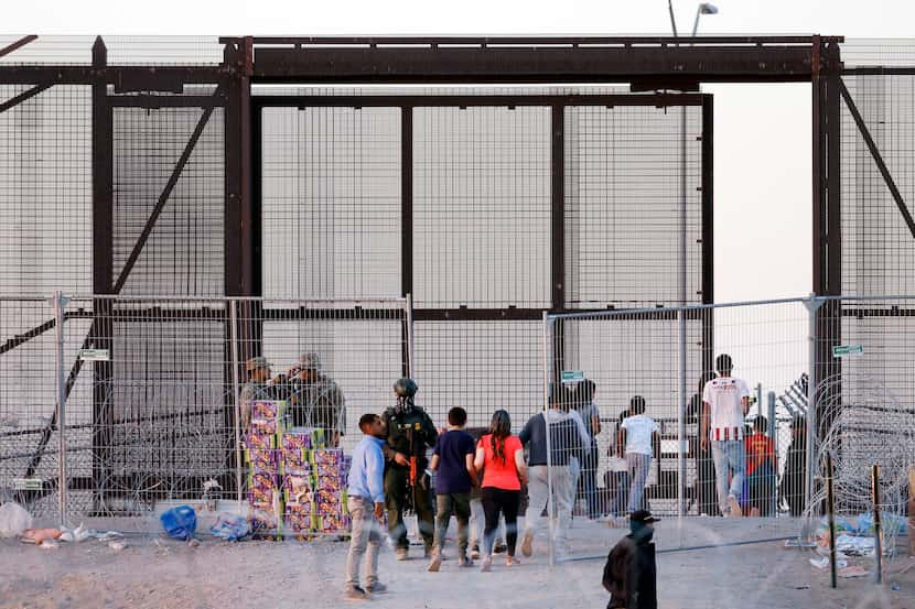 Some migrants are led through Gate 42 to a waiting bus on the U.S. side of the Rio Grande...