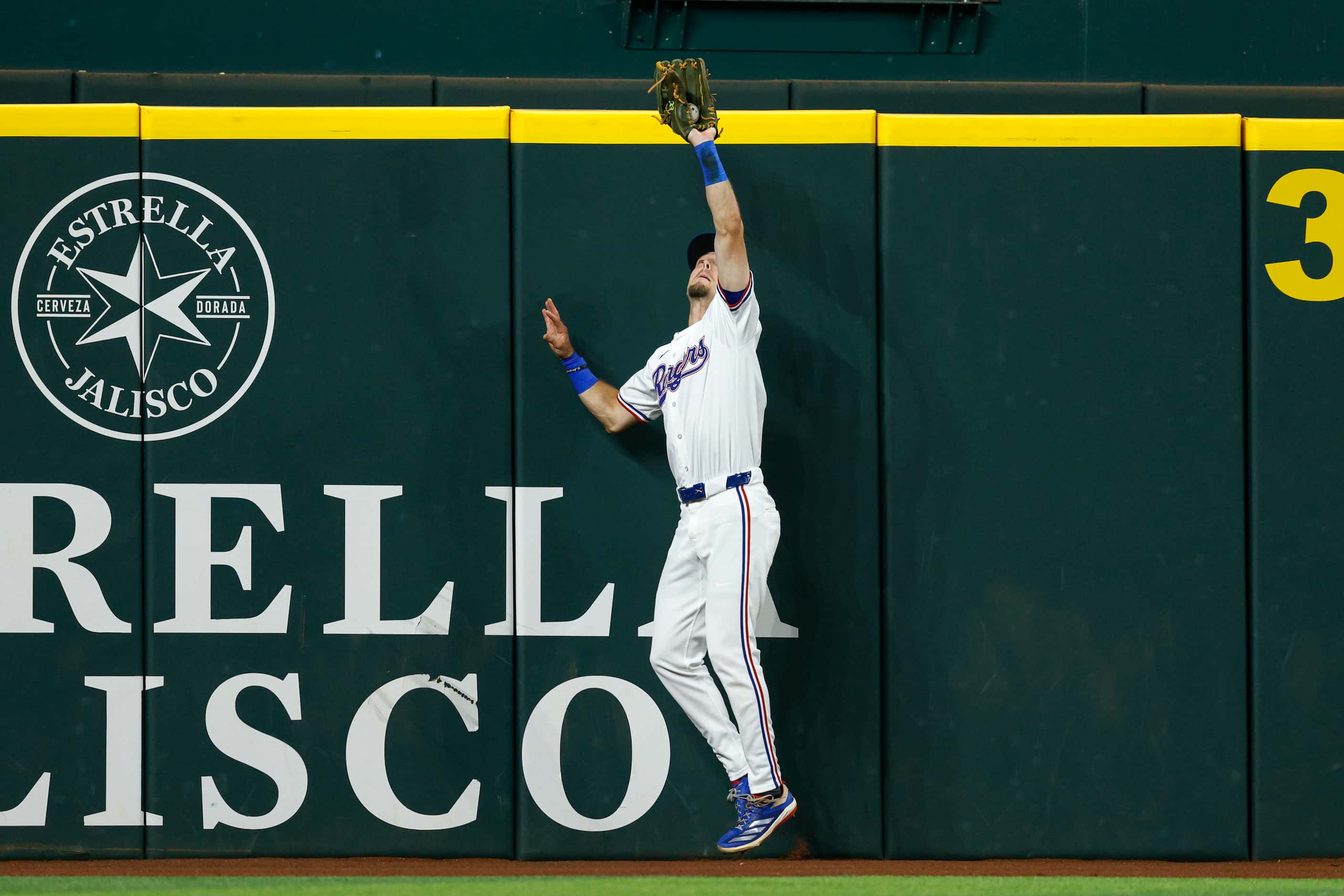 Texas Rangers left fielder Evan Carter (32) make a leaping catch at the wall during the...