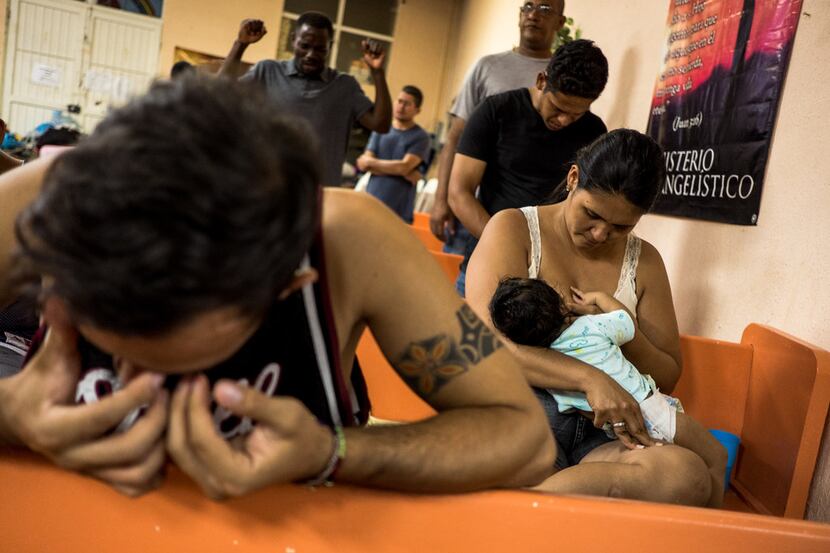Joseph Banegas, 26, left, wipes tears from his eyes during a prayer as his wife Endira...