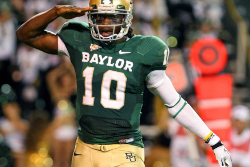 Baylor quarterback Robert Griffin III salutes after throwing a touchdown pass to wide...