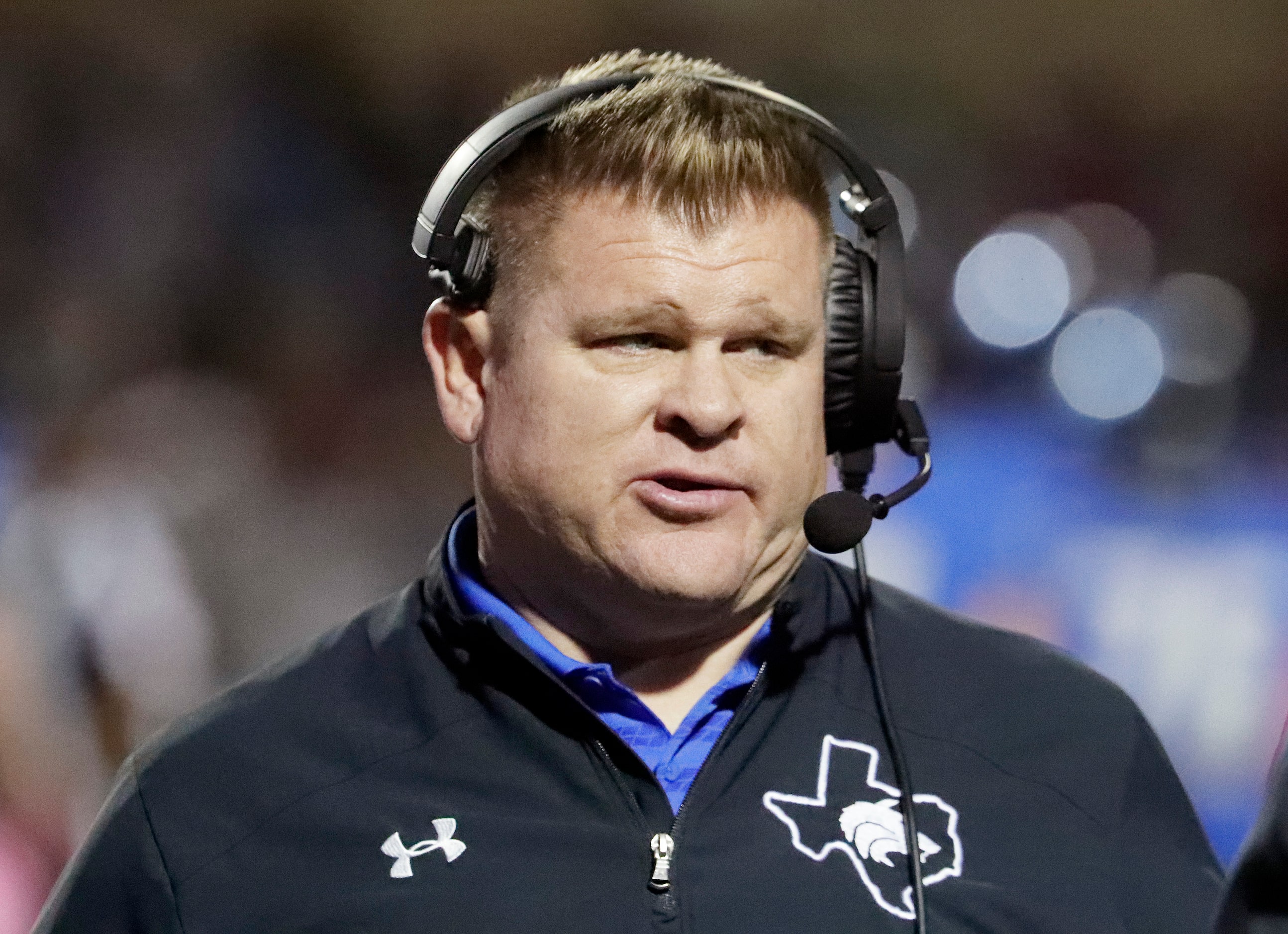 Plano West High School head coach Tyler Soukup talks on his headset during the first half as...