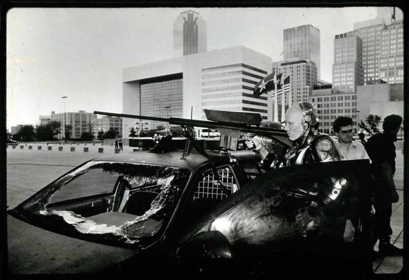 The Dallas skyline looms behind actor Peter Weller as as he prepares to shoot a scene...
