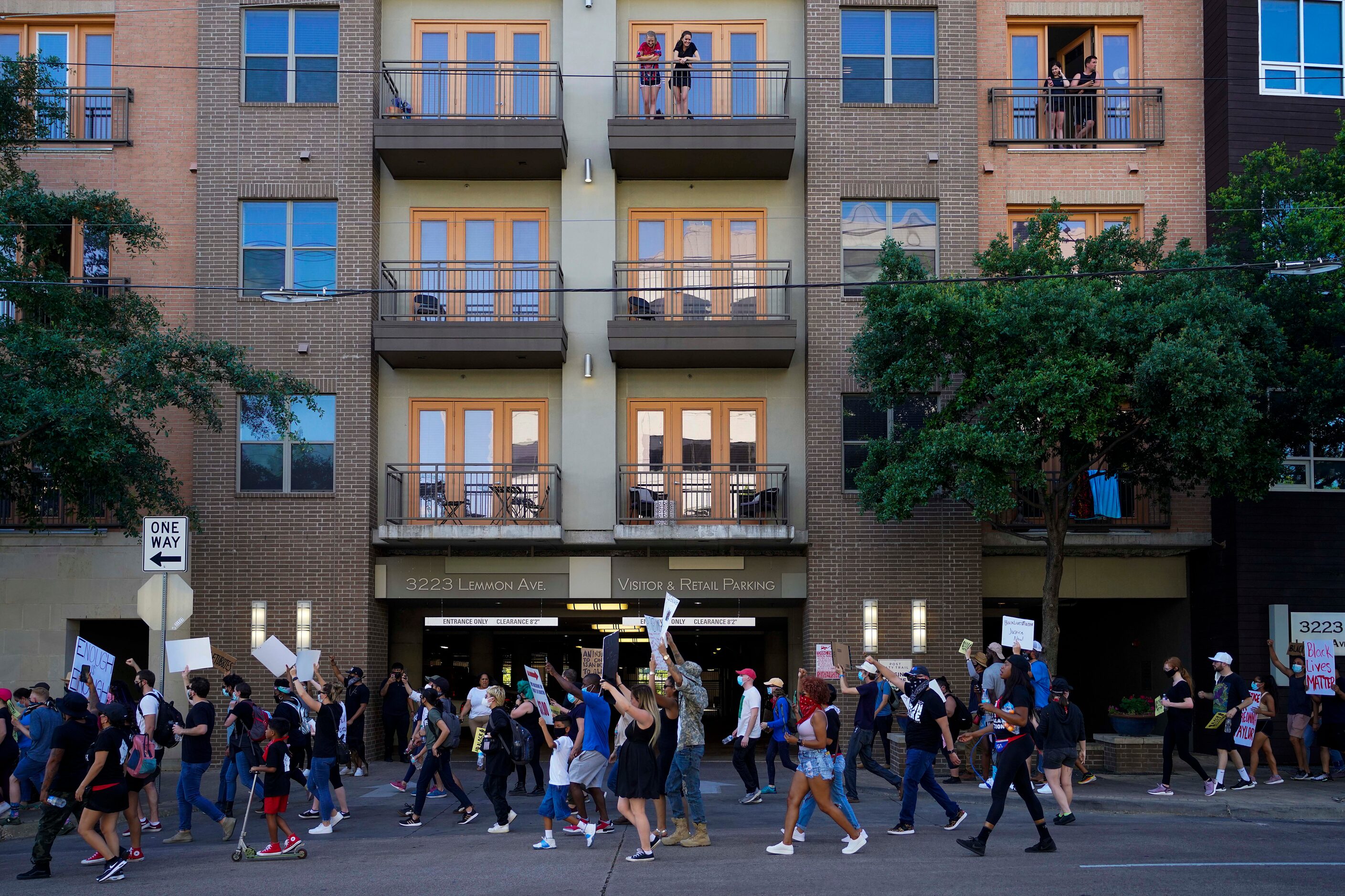 People watch from apartment balconies at the corner of Lemmon Avenue and Carlisle Street as...