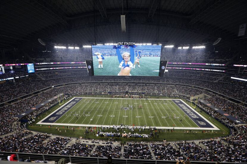 A Dallas Cowboys cheerleader is shown performing on the large video screen inside AT&T...