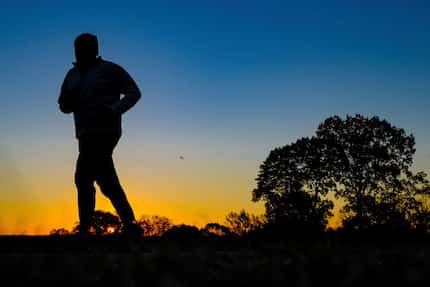 A runner is silhouetted against the sunrise on his early morning workout near Arlington...