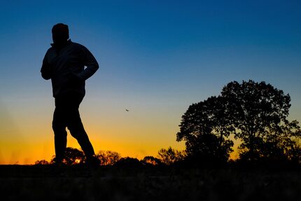 A runner is silhouetted against the sunrise on his early morning workout near Arlington...