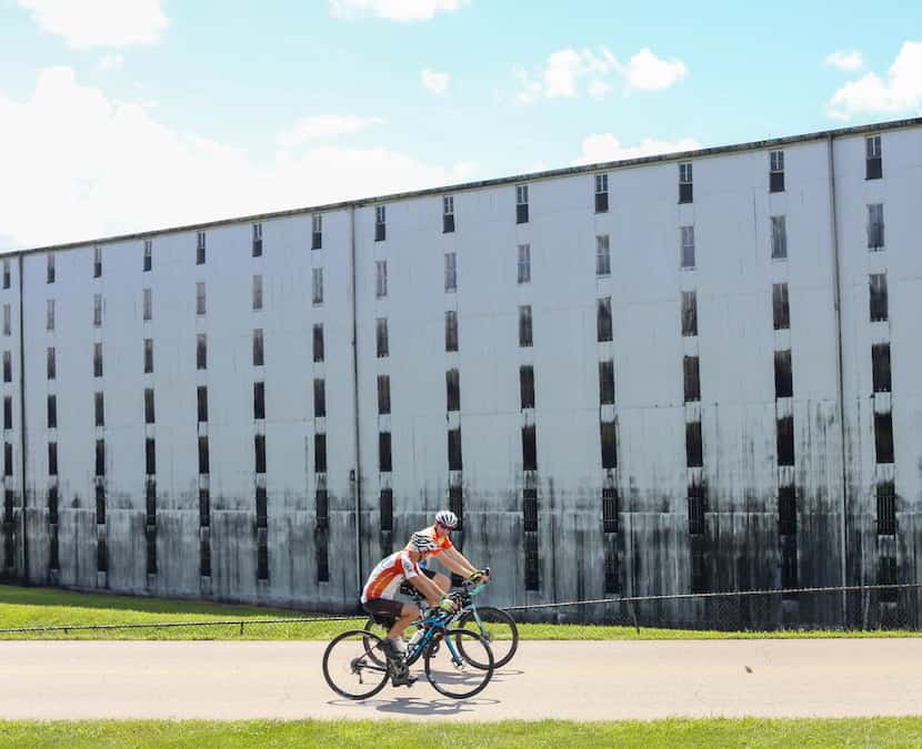 Cyclists ride past a rickhouse -- a building where bourbon barrels age — at Heaven Hill...