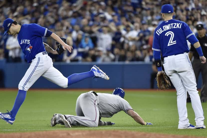 Texas Rangers' Mike Napoli, center, is tagged out by Toronto Blue Jays' Brett Cecil, left,...