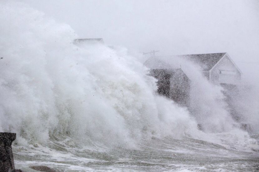 SCITUATE, MA - JANUARY 04: A wave crashes over a homes on Lighthouse Rd. as a massive winter...