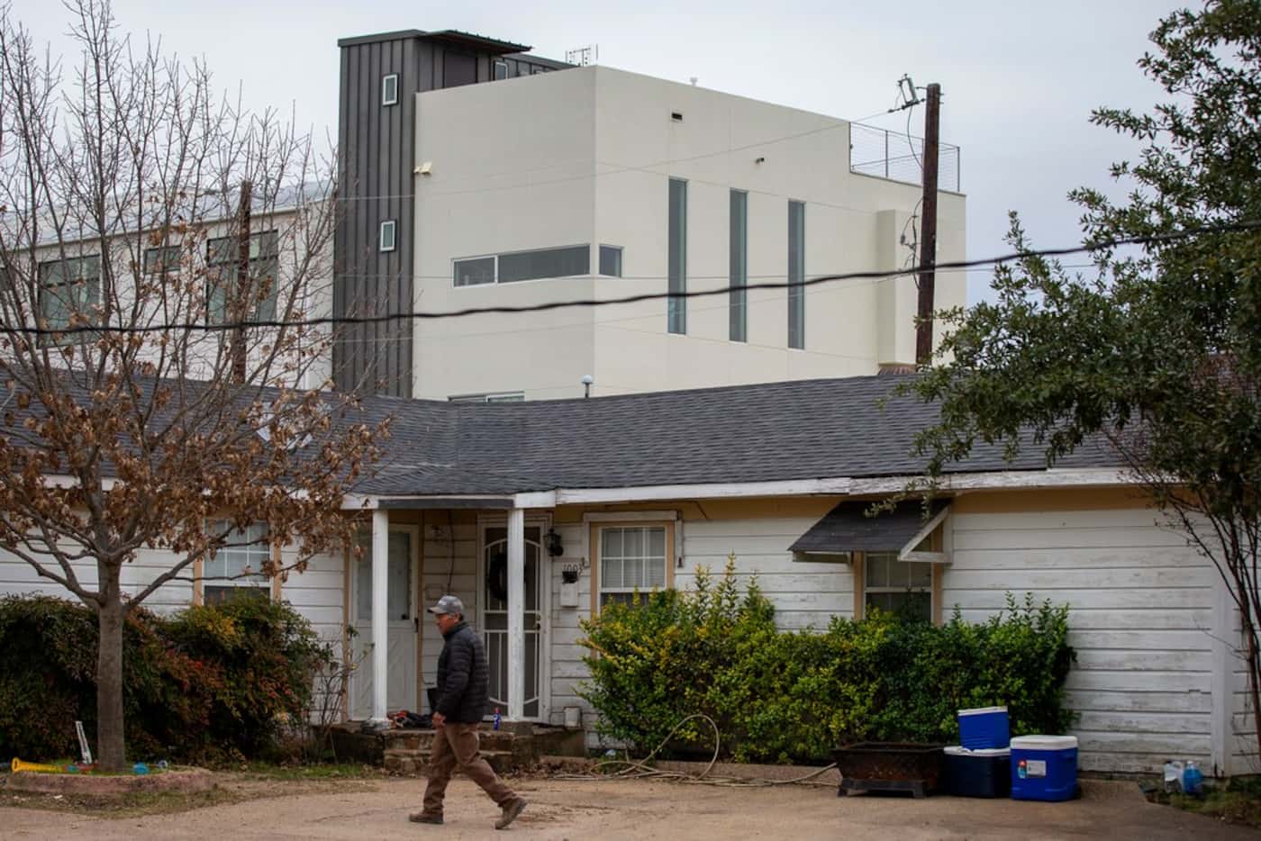 New construction rises over his home as Jose Morin walks between buildings on his property...