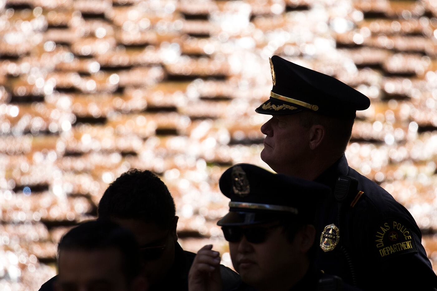 Members of the Dallas police department are silhouetted against the water cascading down the...