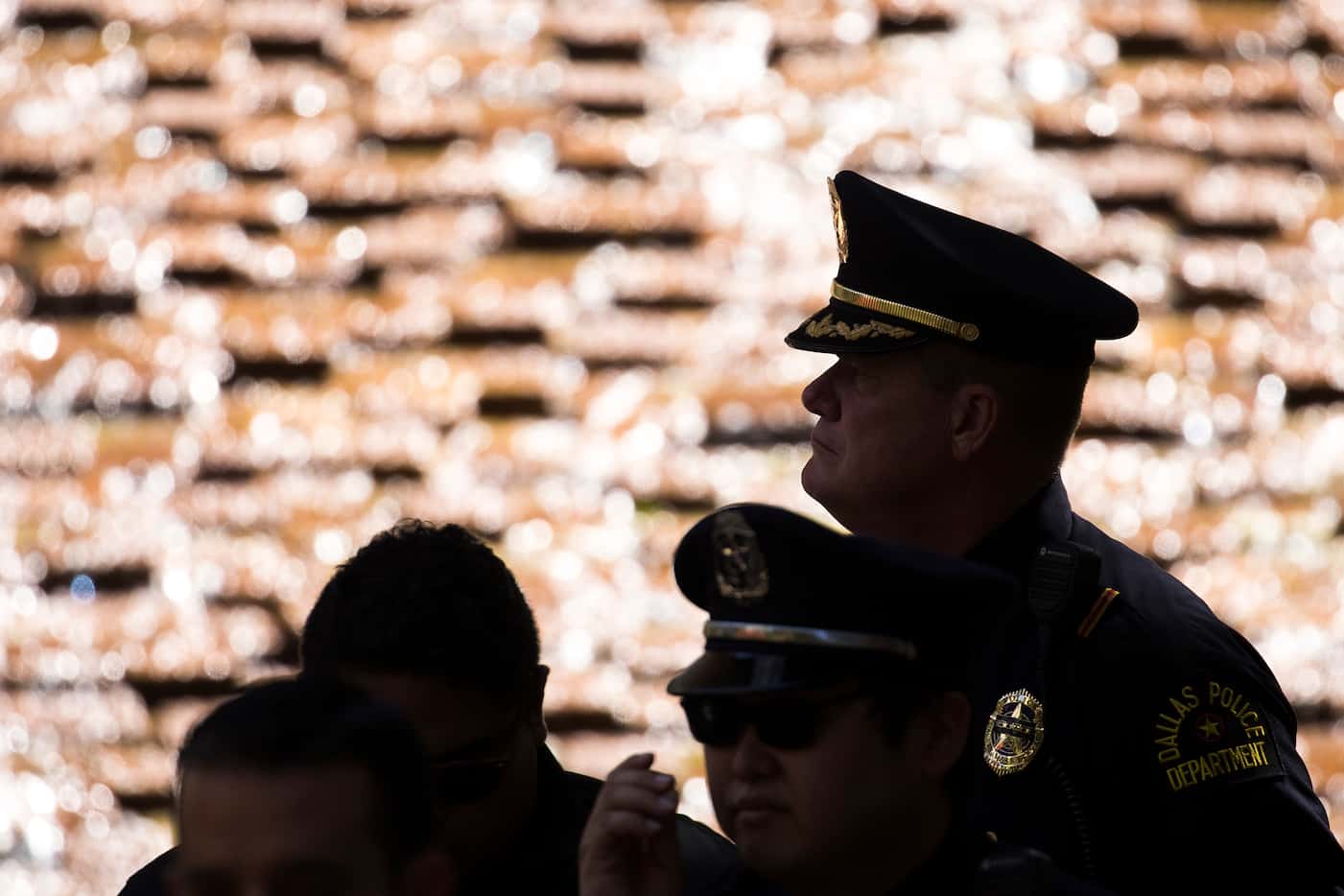 Members of the Dallas police department are silhouetted against the water cascading down the...