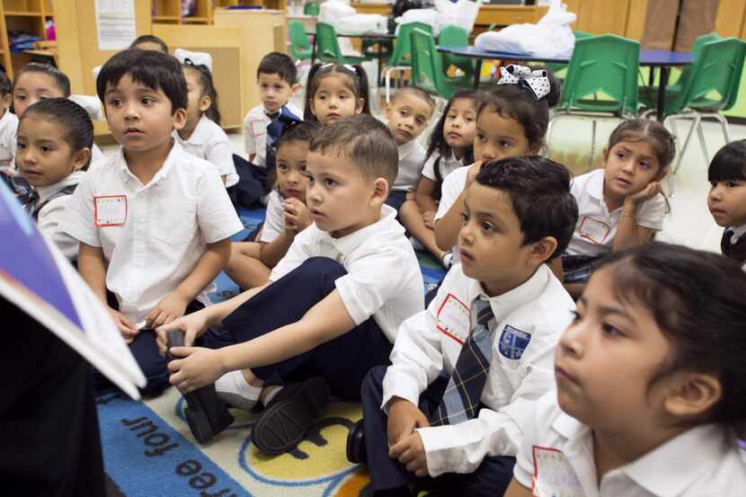 Youngsters in a Dallas prekindergarten class listen as their teacher reads a story on their...