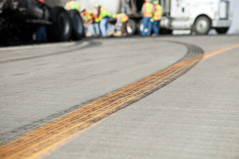 A semi tractor and trailer has crashed on a highway and workers are cleaning up the scene....