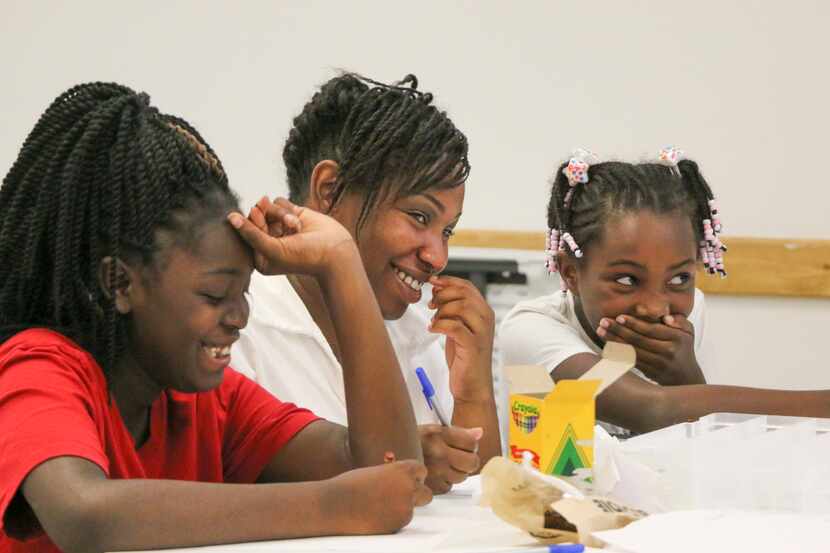 A Black woman and two Black children work on school activities together.