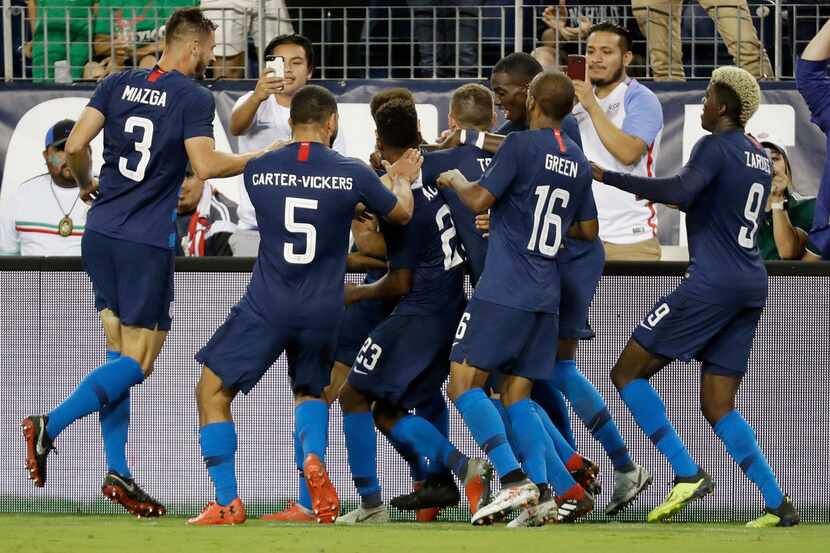United States players celebrate after midfielder Tyler Adams scored a goal against Mexico...