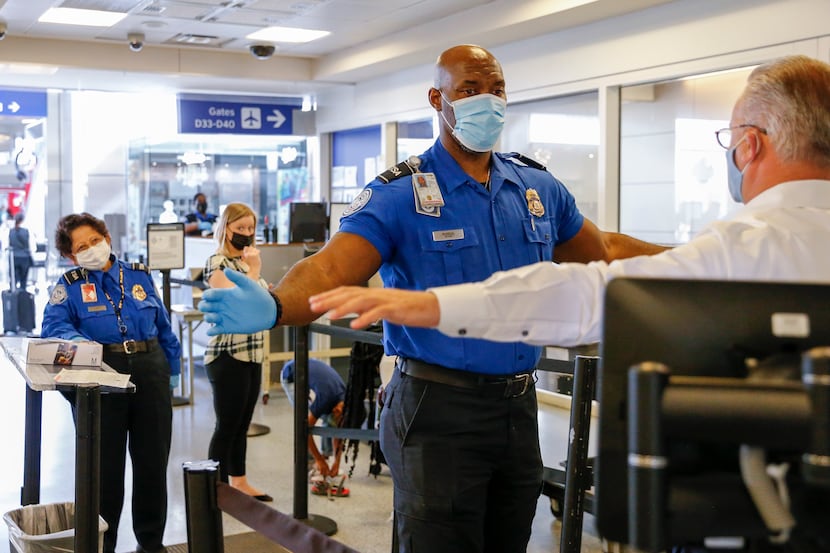 Transportation Security Officer Kevin Blakely assists a traveler during security screening...