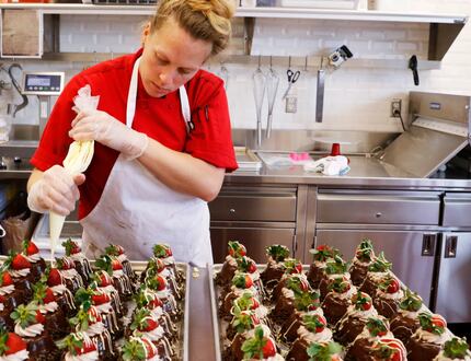 Carrie Castano, cake decorator, puts the finishing touches on chocolate mousse cakes.