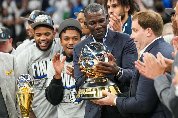 Dallas Mavericks assistant general manager Michael Finley hands the championship trophy to...
