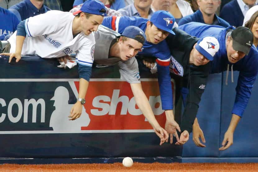 Blue Jays fans reach for a foul ball off the bat of Jose Bautista (19) in the seventh inning...